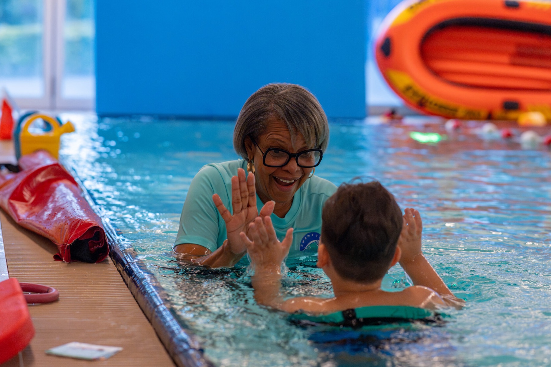 Swimming teacher giving a pupil a high five in the pool